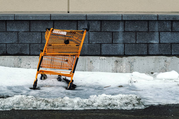 A damaged shopping cart sits in ice behind a supermarket.