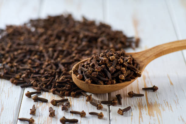 istock cloves spice in a wooden spoon on a light kitchen table. 2202724142