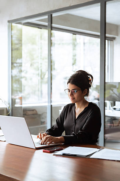 istock Vertical portrait middle eastern woman using computer technology app for work online.Focused professional financial it specialist latin hispanic business lady working on laptop pc sitting in office 2202724778