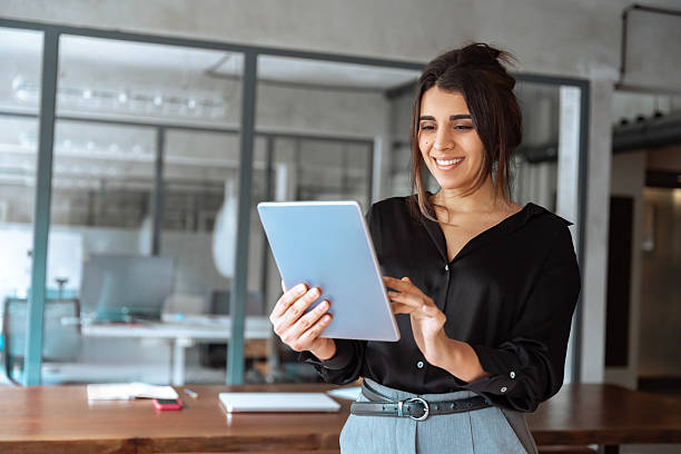 istock Latin Hispanic young professional business woman working on touchscreen computer. Middle eastern Indian businesswoman CEO holding digital tablet using tab application standing at workplace in office 2202724783