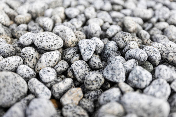 istock Bed of pebbles or smooth rocks and stones with light gray texture 2202726007
