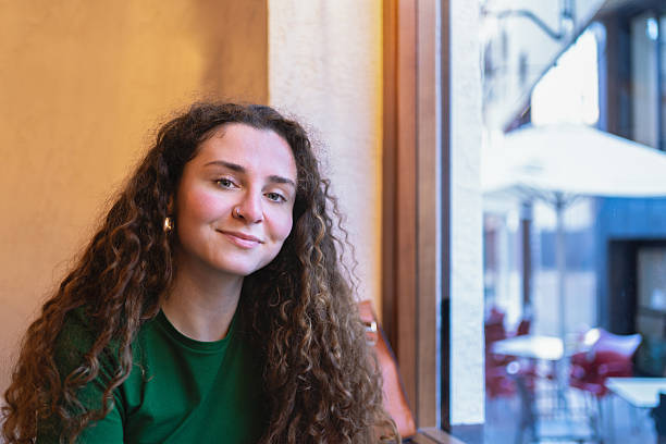 istock Young woman smiling and relaxing in cafe by window 2202731676