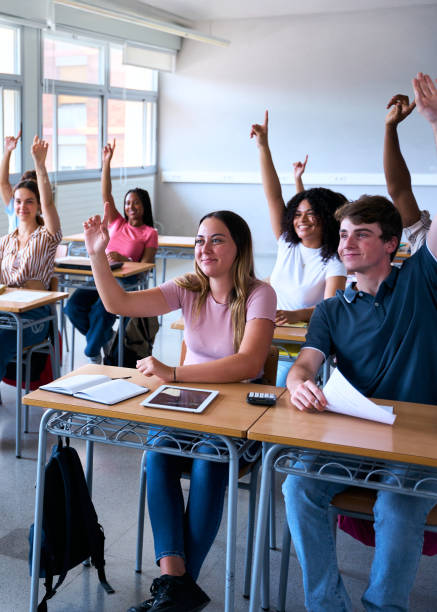 istock Rear view of a student in the classroom raising her hand to ask a question during class 2202732749