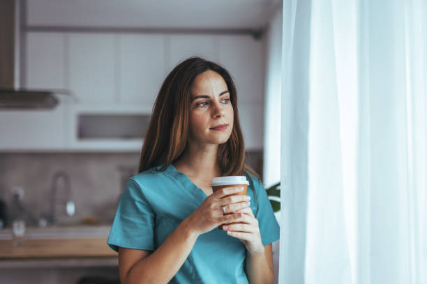 istock Thoughtful Nurse Relaxing With Coffee at Home Near Window 2202738521