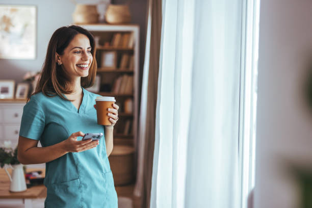 istock Smiling Nurse Enjoys Coffee Break While Using Smartphone at Home 2202738596