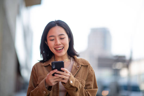 istock smiling young woman using mobile phone in city 2202739485