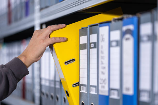 istock Hand Retrieving Yellow Binder from Organized Archive Shelf 2202739564
