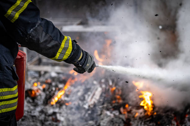 istock Professional Firefighter Extinguishing Flames Through Dense Smoke and Embers 2202739626