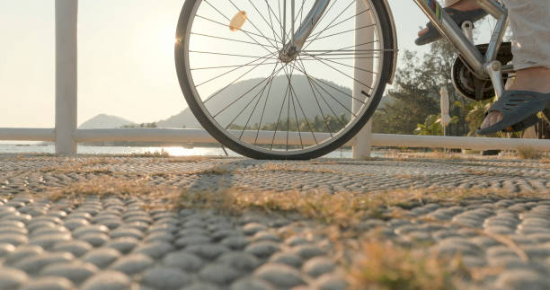 Low angle view of man riding bicycle on pier above sea and mountains in distance,  at sunrise, Phu Quoc Island