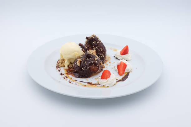 Delightful dessert plate featuring poached pears drizzled with chocolate accompanied by vanilla ice cream and fresh strawberry slices
