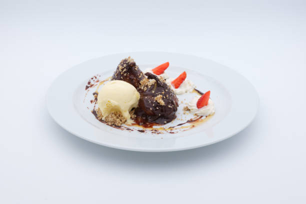 Indulge in this delightful dessert featuring chocolate covered puffs a scoop of vanilla ice cream whipped cream and fresh strawberry slices