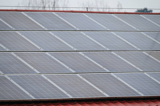 A close-up view of solar panels installed on a red tiled roof, reflecting renewable energy technology. The dark photovoltaic cells contrast with the bright roofing material, emphasizing sustainability and modern energy solutions.