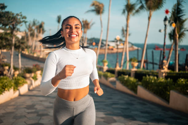 istock Joyful Hispanic Woman Jogging on Seaside Walkway 2202749696