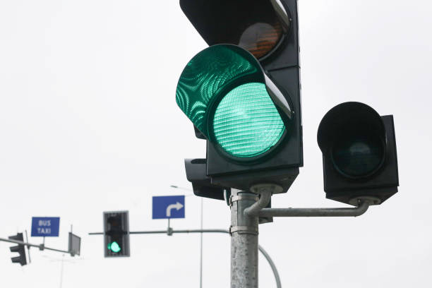 istock Green traffic light at an intersection on a cloudy day. Road safety and transportation control signal. 2202750920