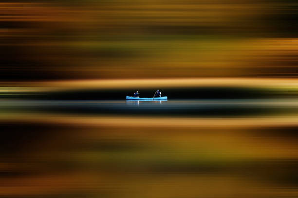 Two people canoeing across a lake with a long exposure effect creating an abstract image with horizontal lines