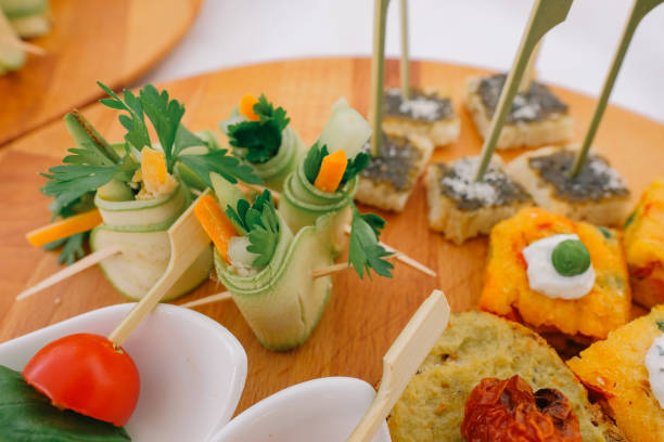 istock Assorted mini snacks with zucchini rolls bread and tomato The snack bites are presented on a wooden serving board with white ramekins 2202751771
