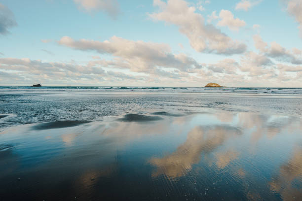 The wet sand reflects the vast sky, creating a mesmerizing mirror effect as gentle waves roll in.