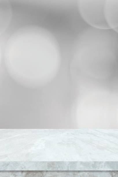 istock Empty vertical white table top, counter, desk background over blur perspective bokeh light background, White marble stone table, shelf and blurred kitchen restaurant for food, product display mockup, template 2202759877