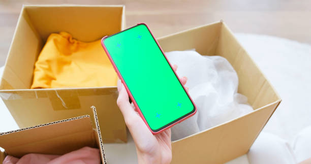 point of view closeup asian woman unboxing online shopping items at home using a green screen smartphone