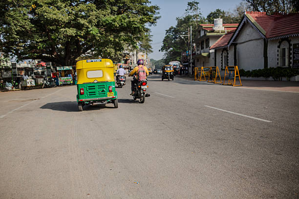 Mysore, India - January 2, 2025. An auto rickshaw and motorcyclist drive beside each other in Mysore, India.