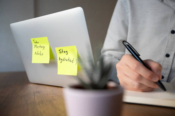 istock A man in a white shirt is working on a laptop with two pop-up notes attached. One says 