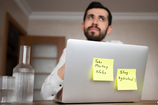 istock A man in a white shirt is working on a laptop with two pop-up notes attached. One says 