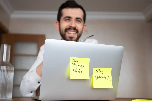 istock A man in a white shirt is working on a laptop with two pop-up notes attached. One says 