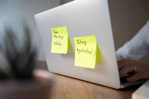 istock A man in a white shirt is working on a laptop with two pop-up notes attached. One says 