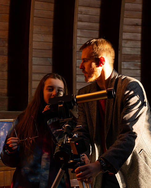 istock Man teaches young girl how to use solar telescope 2202776071