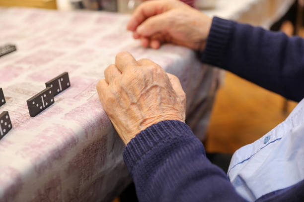Elderly hands playing dominoes close-up.