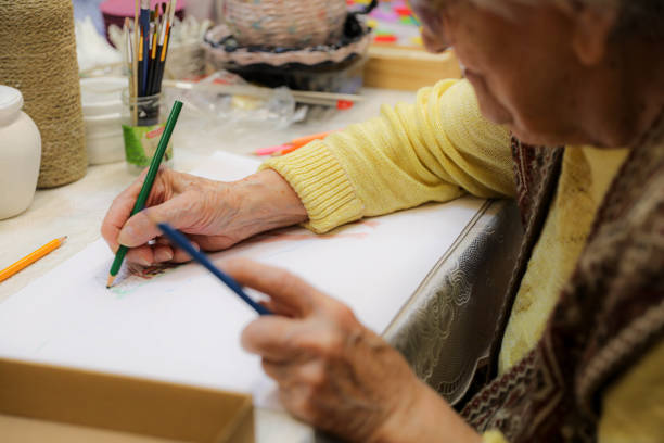 istock Close Up Senior Hands Drawing And Coloring 2202776696