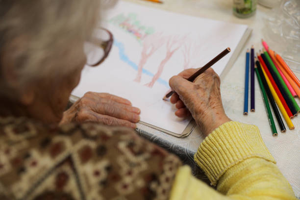 istock Close Up Senior Hands Drawing And Coloring 2202776788