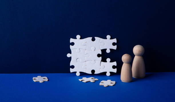 istock Business people completing white jigsaw puzzle on blue background 2202781179