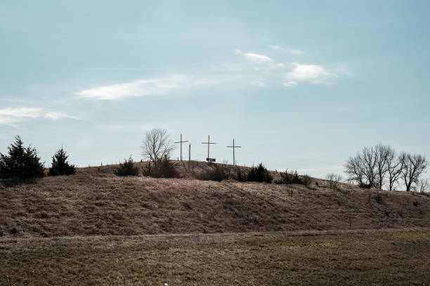 Landscape photo of three crucifixes sitting atop a hill alongside a highway in Nebraska