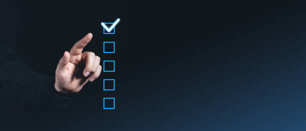 istock Hand pointing at glowing checkbox on dark background, checklist concept. 2202785642