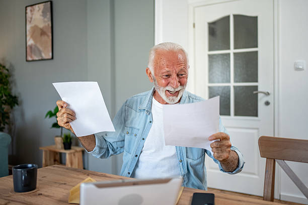 istock Happy senior man reading good news on documents at home 2202786892