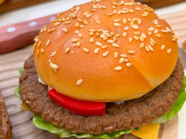 Image of realistic plastic cheeseburger with sesame seed bun / lifelike fake food for display, photography, or prop use