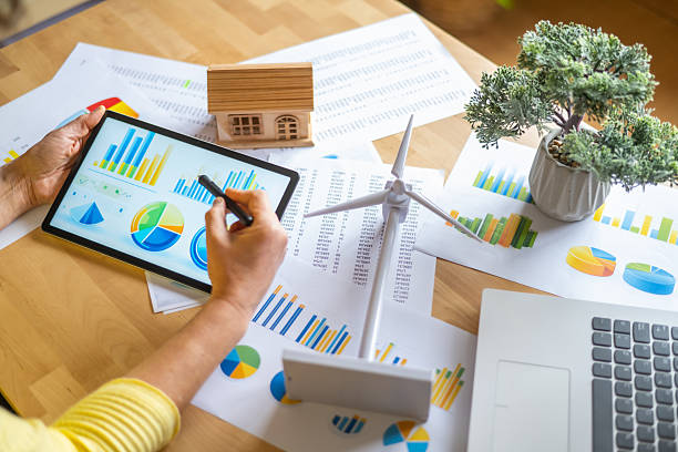 istock Businesswoman analyzing data on a digital tablet for sustainable energy development, focusing on wind and solar power for residential buildings and evaluating renewable resource charts 2202790897