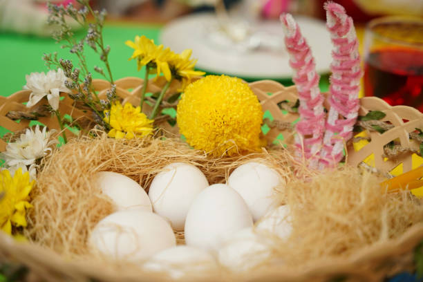 A basket with fresh eggs and vibrant flowers on a table for Easter.