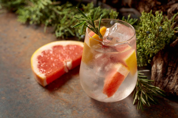 istock Cocktail: gin and tonic with ice, grapefruit, and rosemary on a rustic background. 2202793542