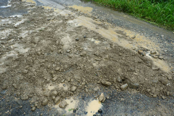Muddy and potholed road in rural area after rain, very muddy road