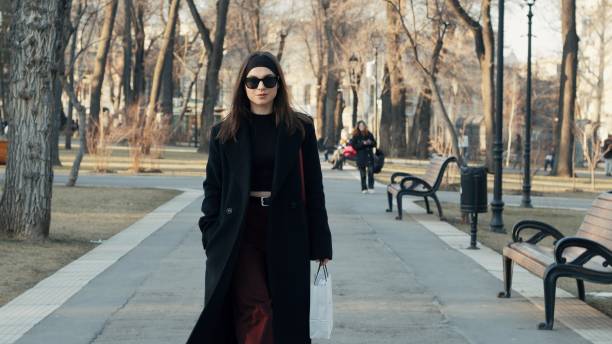 istock Stylish young woman walking in a park during early spring 2202794773