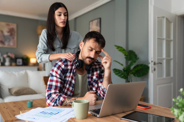 istock Young woman support her man massaging him while he work on laptop computer in home office, stressed with neck or headache pain. Love and respect. Couple simple living concept. 2202804989