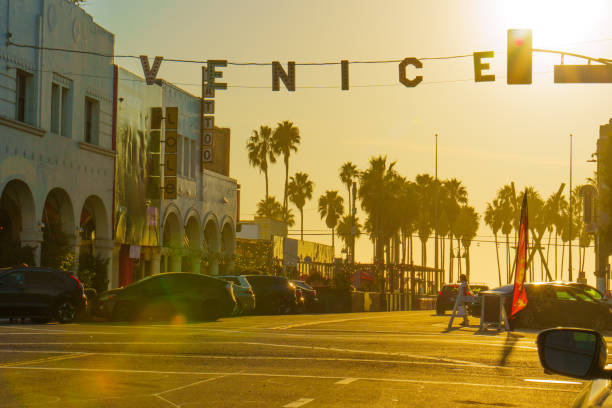 Los Angeles, California - December 18, 2024: Warm sunlight casts a golden hue on Windward Avenue, showcasing the iconic Venice sign and palm trees lining the street.