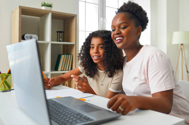istock Caring African American mother using laptop to help her daughter with school homework. 2202809915