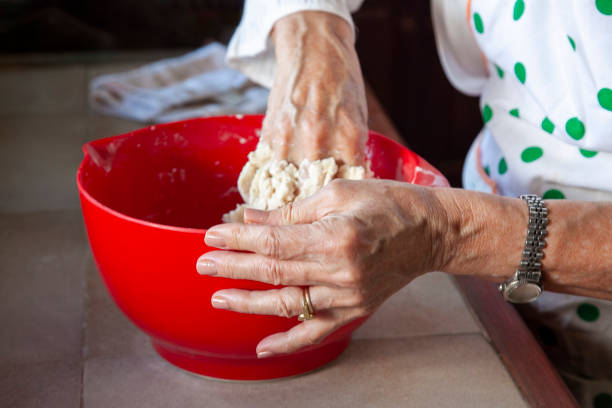 istock Senior woman kneading dough in red bowl, baking preparation 2202811043