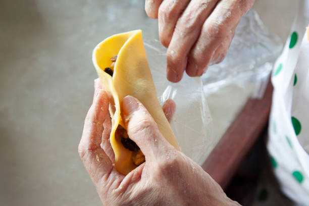 Chef skillfully folding and sealing empanada dough, enclosing a savory filling, highlights expertise in traditional cuisine while showcasing the artistry of culinary preparation