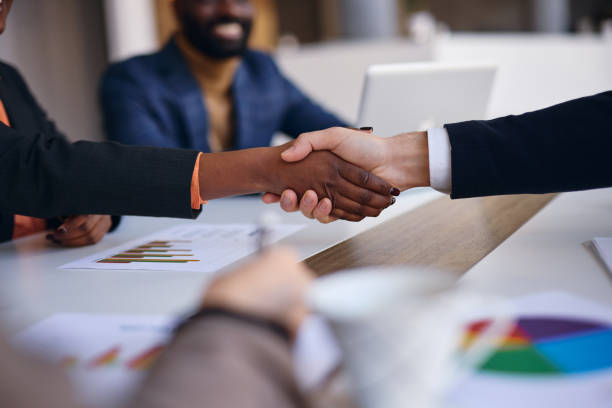 istock Businesspeople shaking hands over a meeting table in a modern office 2202814410