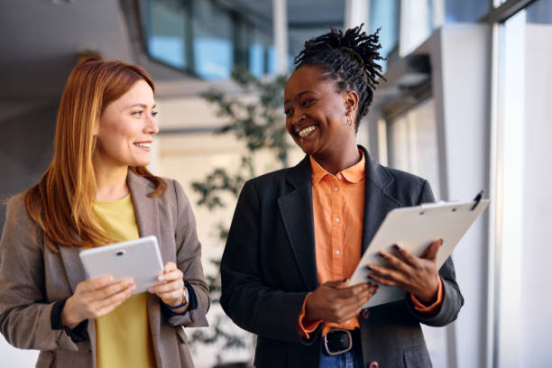 istock Two businesswomen smiling and talking while walking in a modern office 2202814490
