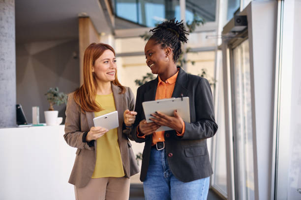 istock Businesswomen using tablet and clipboard walking in modern office 2202814494